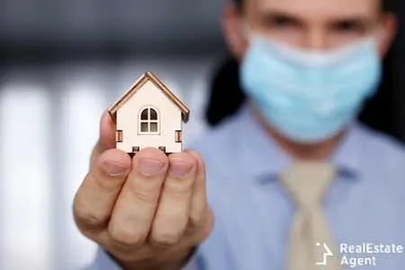 real estate agent and wooden house model in hands