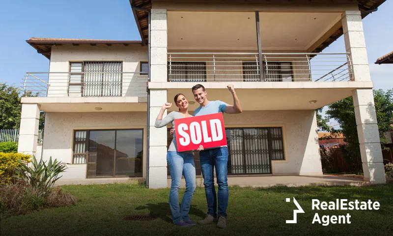 Couple holds a sold sign in front of the store