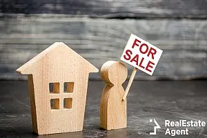 man stands near a house with post for sale